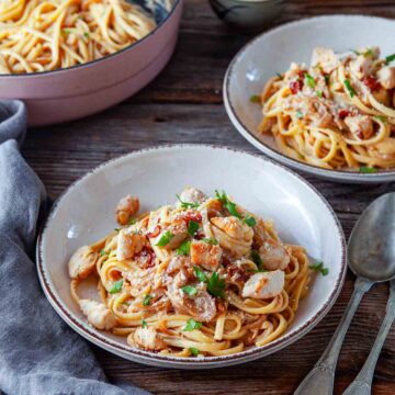 Close up of chicken linguine tossed with tender pasta, juicy chicken pieces, and a rich, savory sauce, finished with herbs and a sprinkle of cheese.