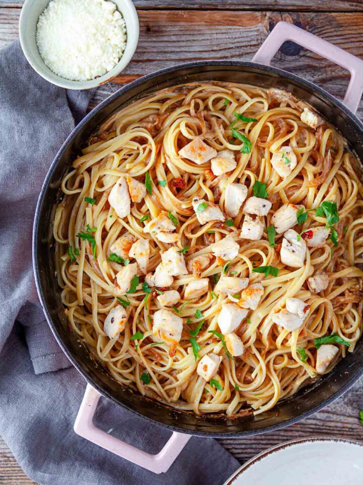 Chicken tossed with pasta in a skillet.