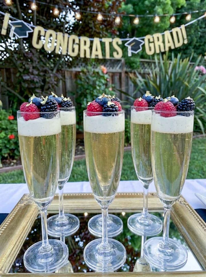 Six champagne flutes filled with champagne jelly and berries.