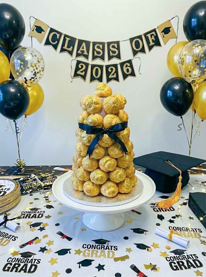 Cream puff tower placed on a dessert table with graduation theme decor.