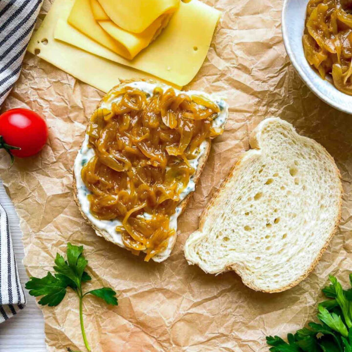 Bread slice with spread and caramelized onions, cheese nearby