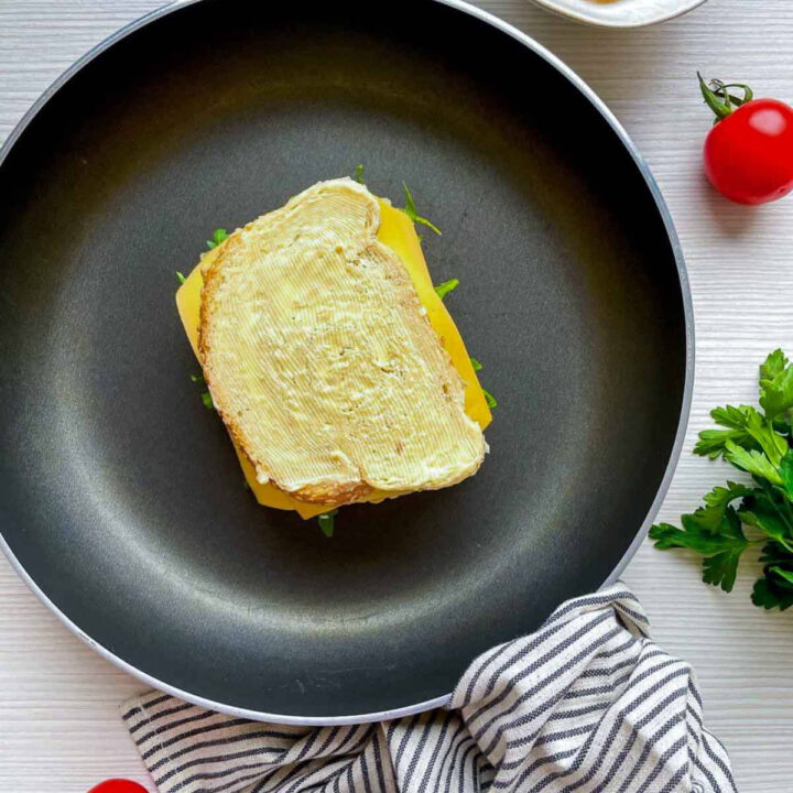 Grilled cheese sandwich cooking in a skillet with buttered bread