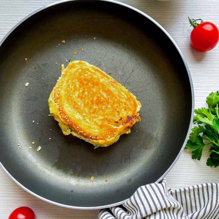 Golden grilled cheese sandwich browning in skillet