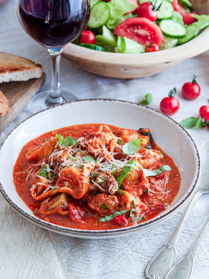 Italian sausage tortellini in tomato sauce with basil, parmesan, salad, and red wine