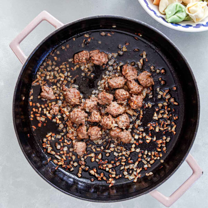Sausage and diced onions browning in a skillet