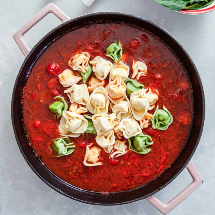 Tomato sauce with sausage and cherry tomatoes simmering in a skillet