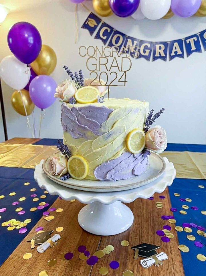 Lemon lavender cake decorated with lemon slices and flowers for a grad party.