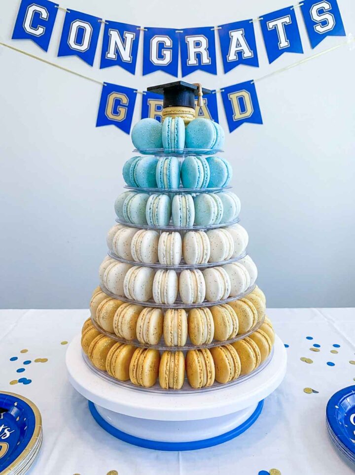 A tall stack of macarons in various colors for a graduation dessert table.