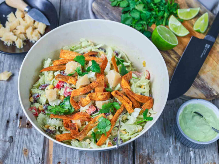 The finished salad is topped with crispy strips, fresh herbs, and cheese, adding texture and a burst of flavor.