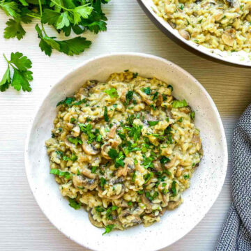 Close up of a bowl of mushroom herb rice garnished with fresh herbs.