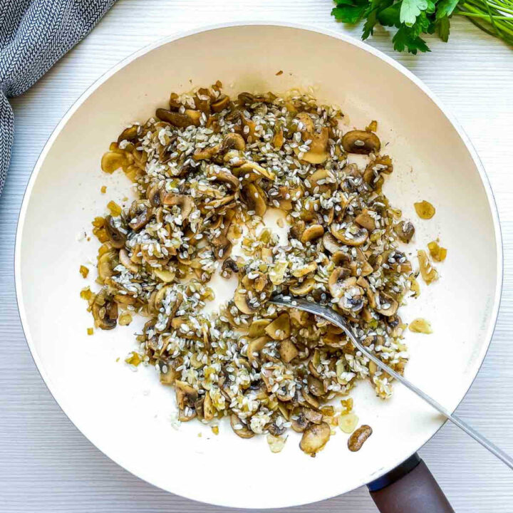 Rice added to sautéed mushrooms and onions in pan