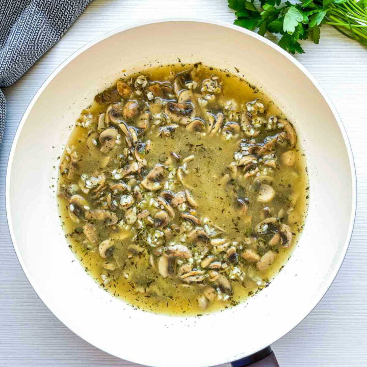Broth added to mushroom and rice mixture simmering in pan.