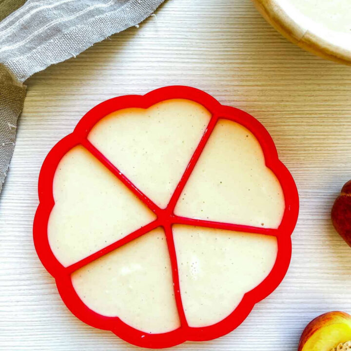 Waffle batter poured into a red segmented waffle mold