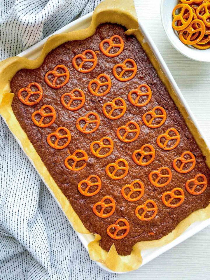 Brownie batter in lined pan topped with pretzels