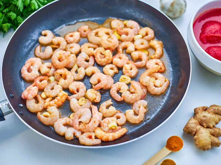 Shrimp are sautéed with garlic until lightly cooked, releasing their flavor and forming the base of the dish.