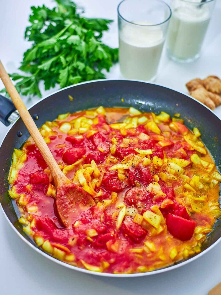 A rich tomato-based sauce with spices and aromatics simmers, building the bold, creamy flavor of the dish.