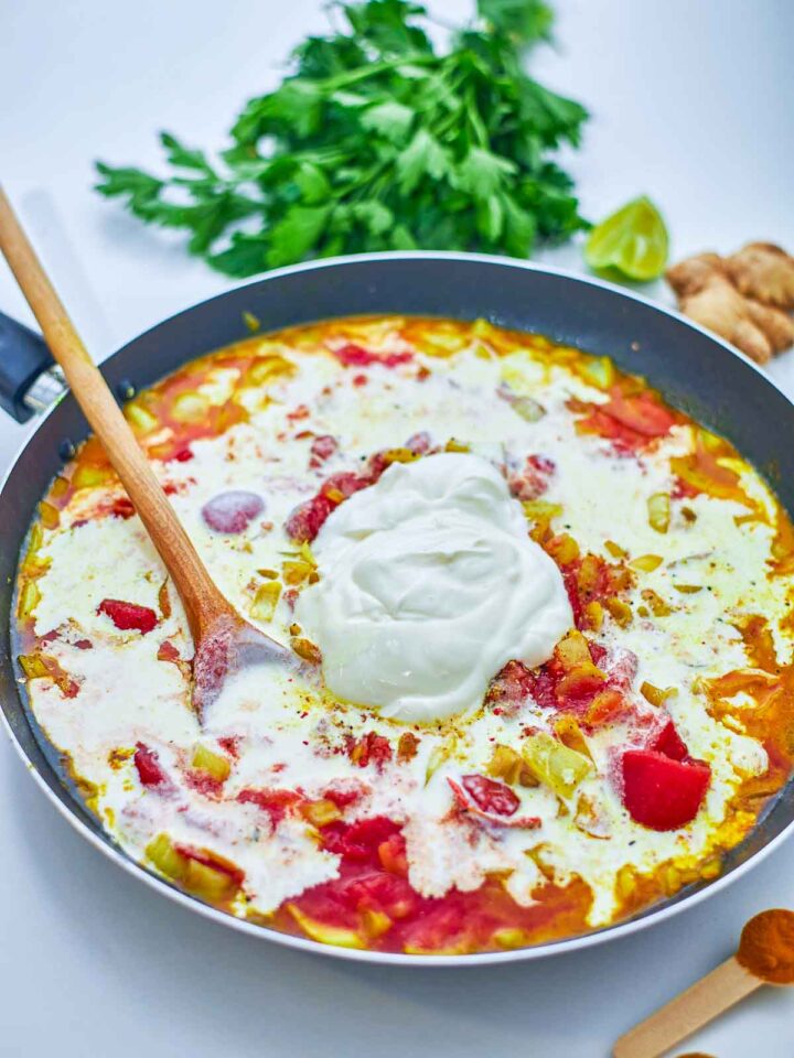 A rich tomato-based sauce with spices and aromatics simmers, building the bold, creamy flavor of the dish.