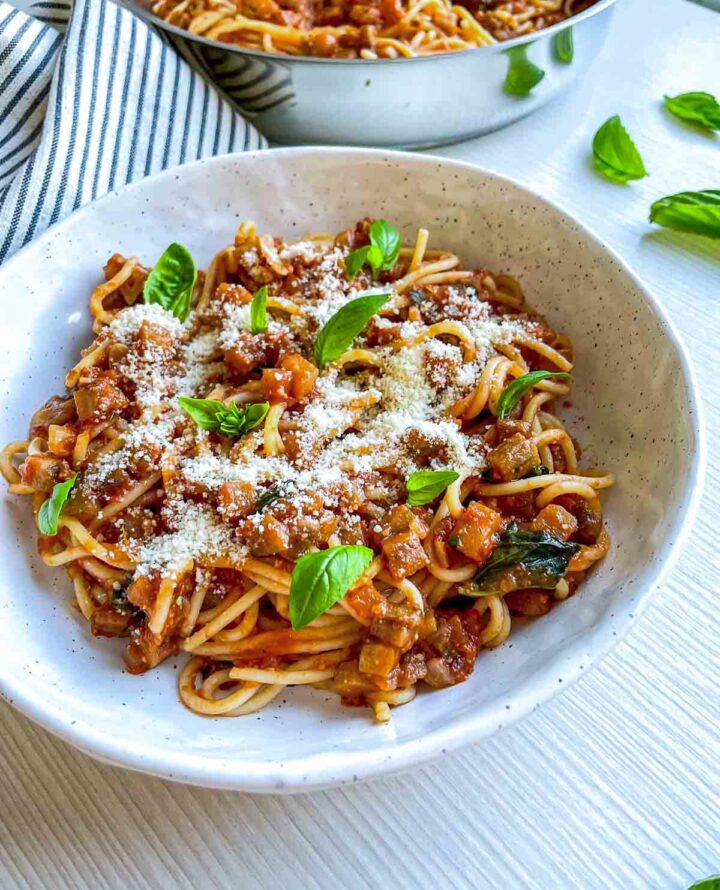 Side view of spaghetti alla norma in a white serving bowl.