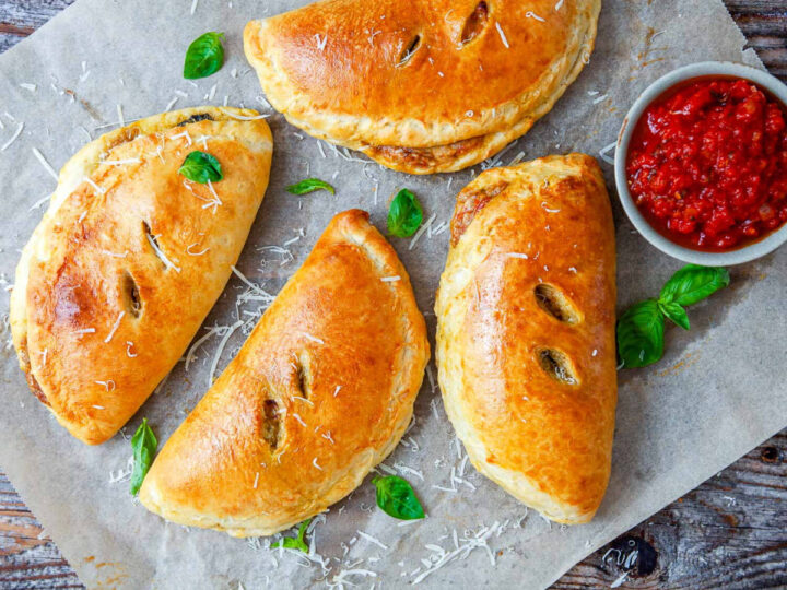 Golden-brown chicken pesto calzones baked until crisp and served with marinara sauce and fresh basil.