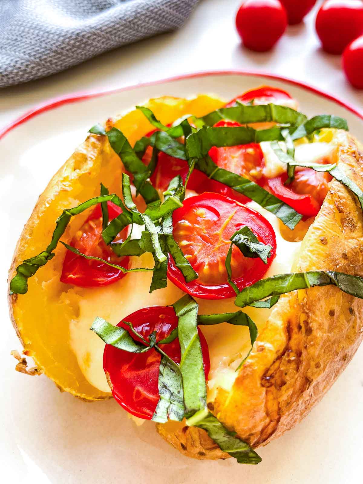 Two baked potato halves layered with sliced fresh mozzarella and halved cherry tomatoes before the second bake.