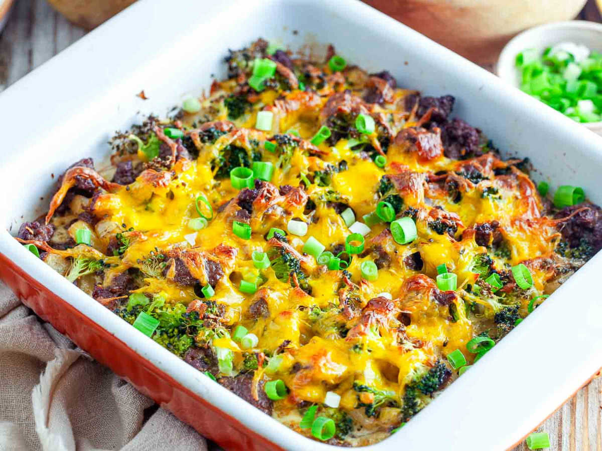 The baked potato sausage broccoli breakfast casserole in its dish, topped with melted, browned cheddar and sliced scallions.