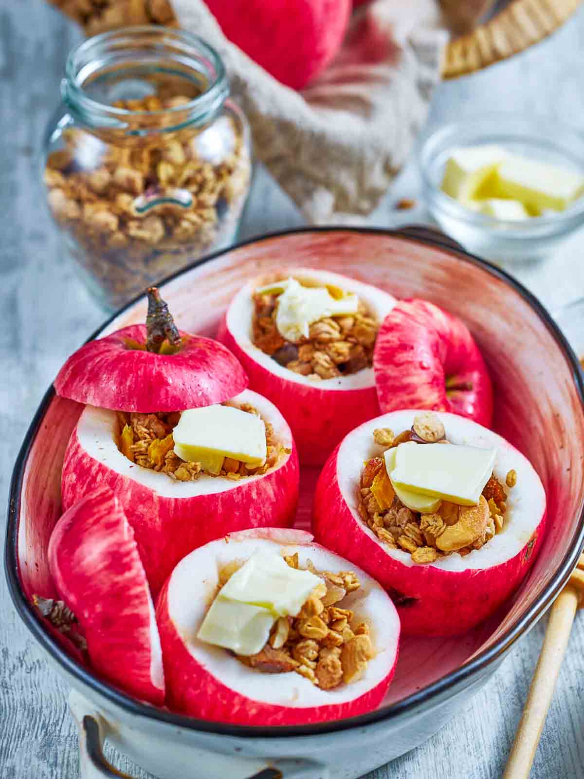 granola-filled apples each topped with a pat of butter, ready to go into the oven