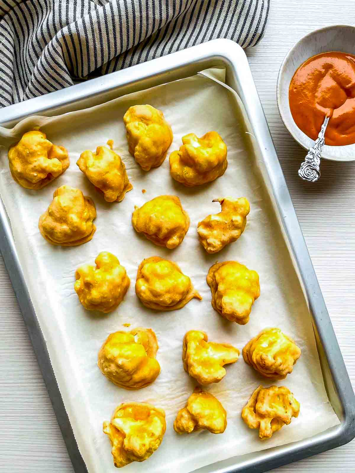  Battered cauliflower florets baked until lightly golden on a parchment-lined baking sheet
