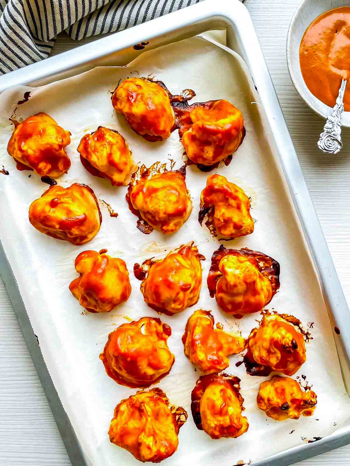 Crispy buffalo cauliflower with deep golden edges on a parchment-lined baking sheet after the final bake