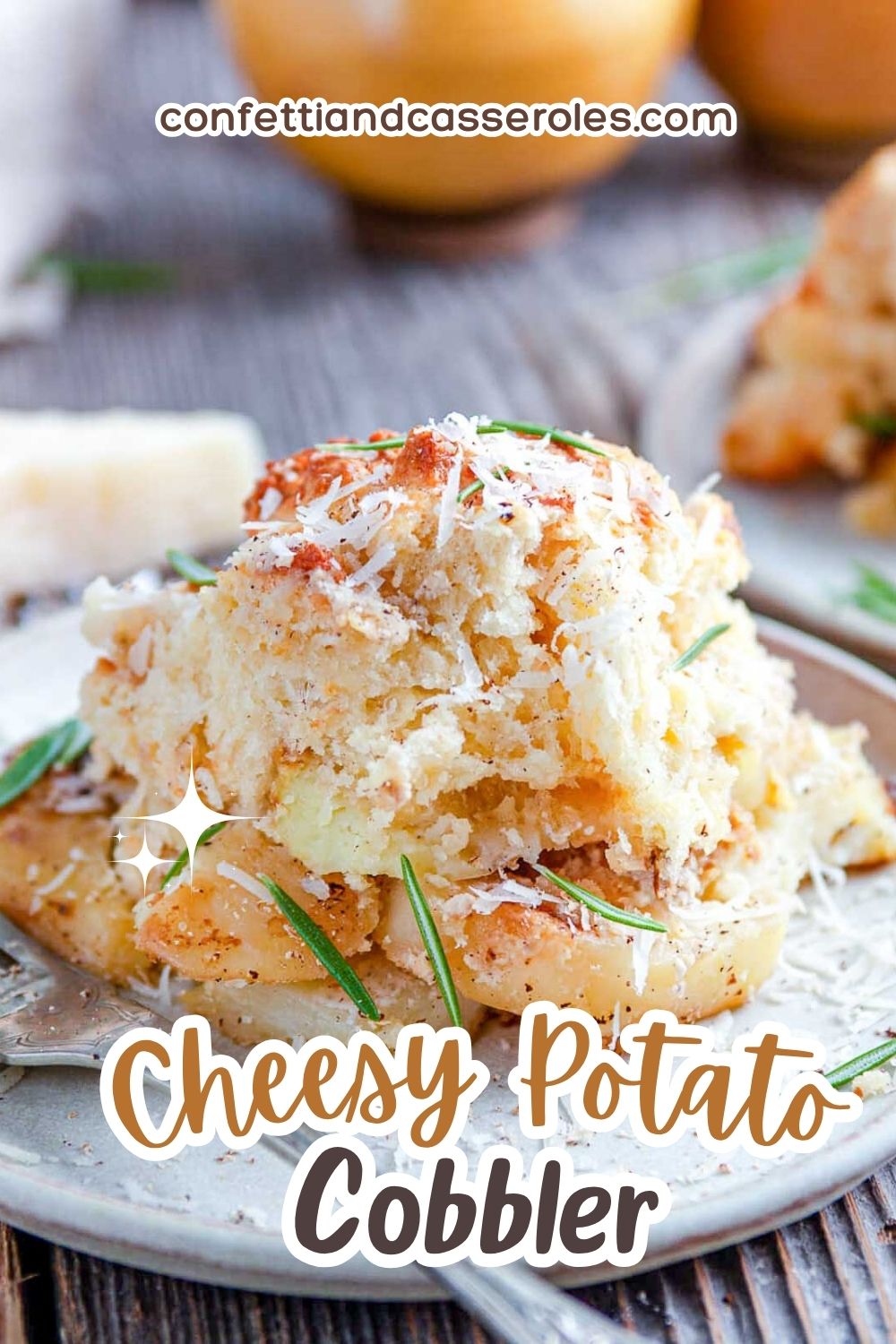 Cheesy potato cobbler with a golden drop biscuit topping over creamy sliced potatoes, piled on a plate and finished with parmesan and rosemary.