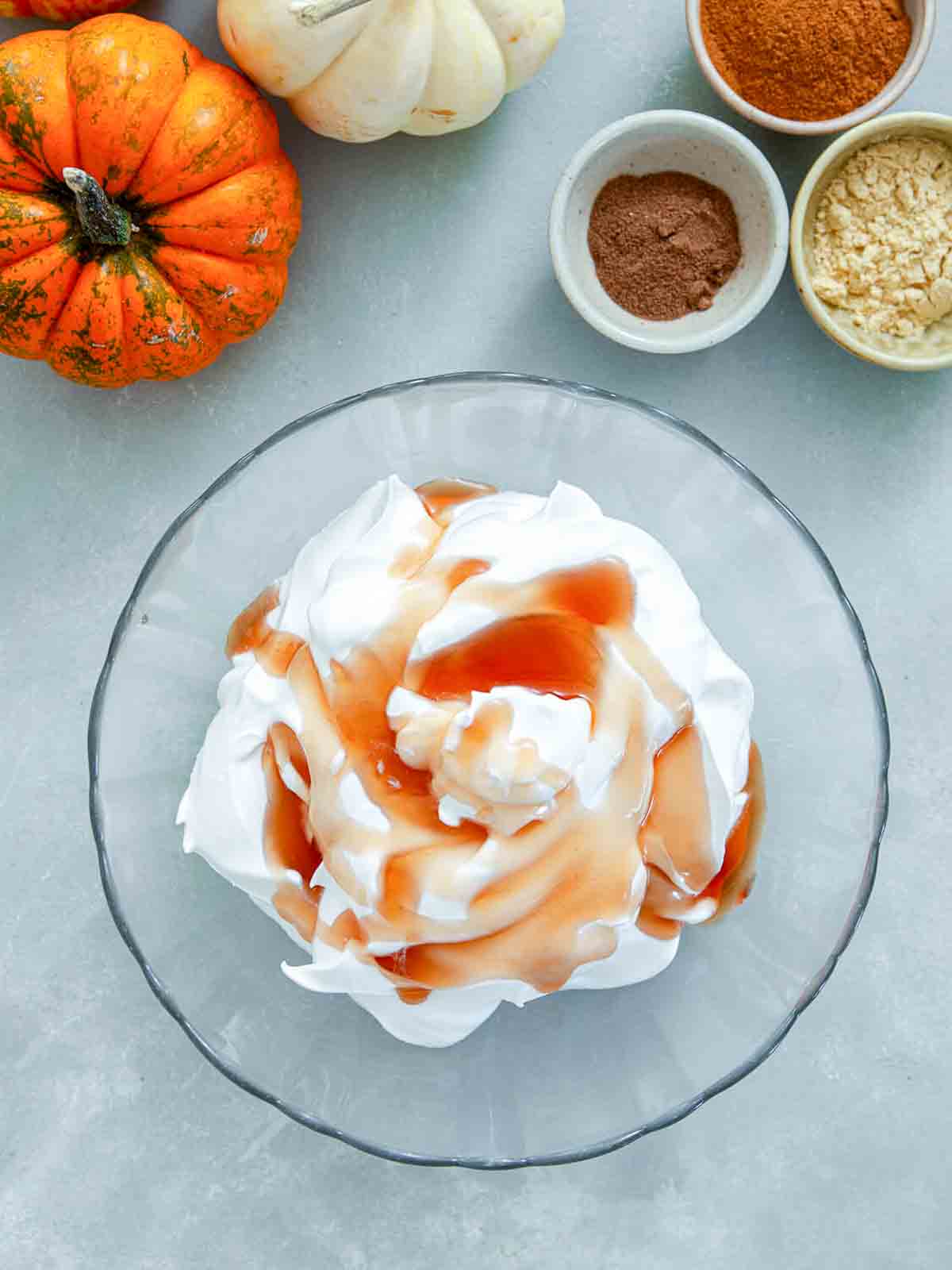  Fluffy whipped cream in a glass bowl with amber maple syrup drizzled over the top